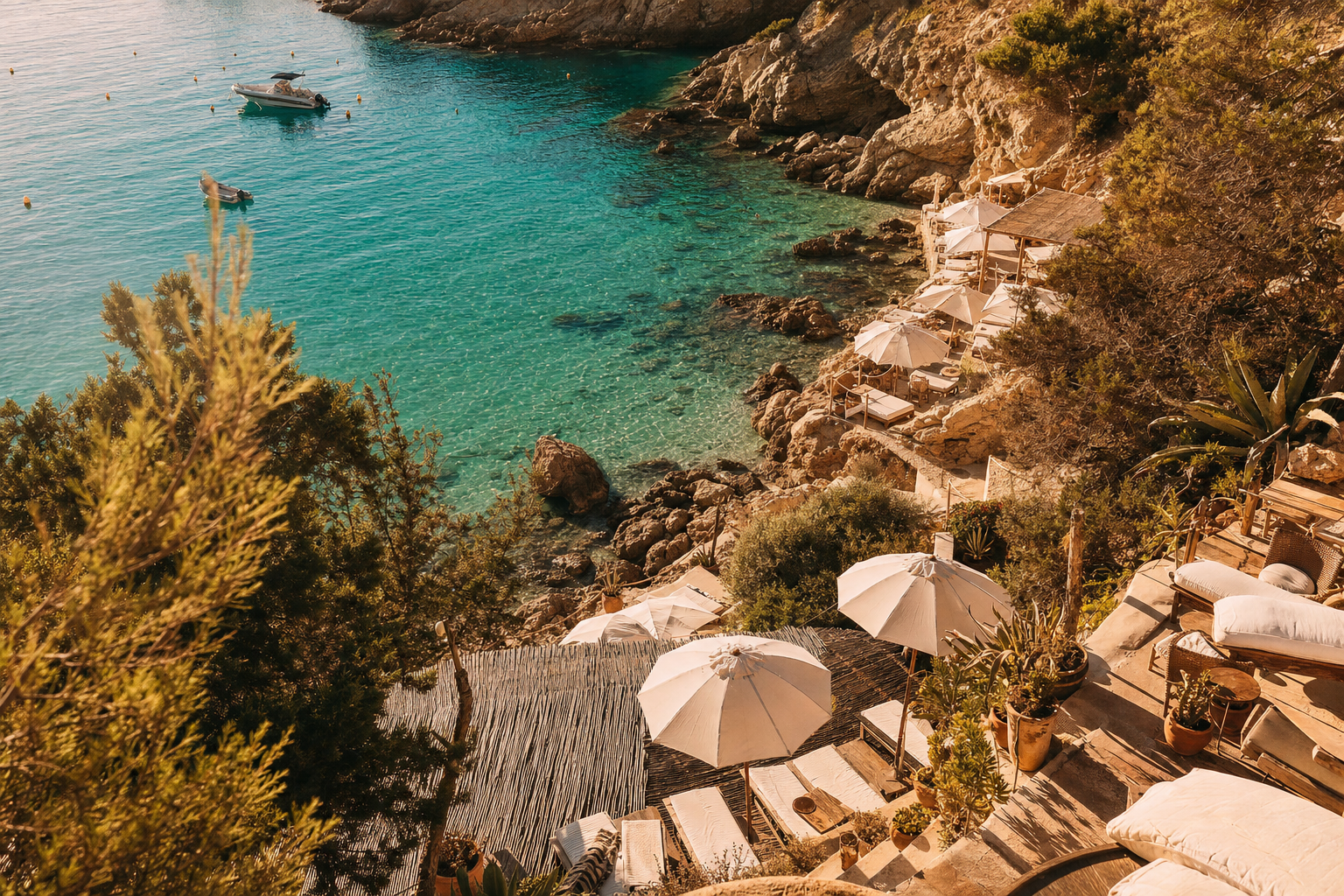 Vista aérea de la cala de Port des Torrent en Ibiza a la hora dorada con aguas turquesas y el beach club Alma Beach